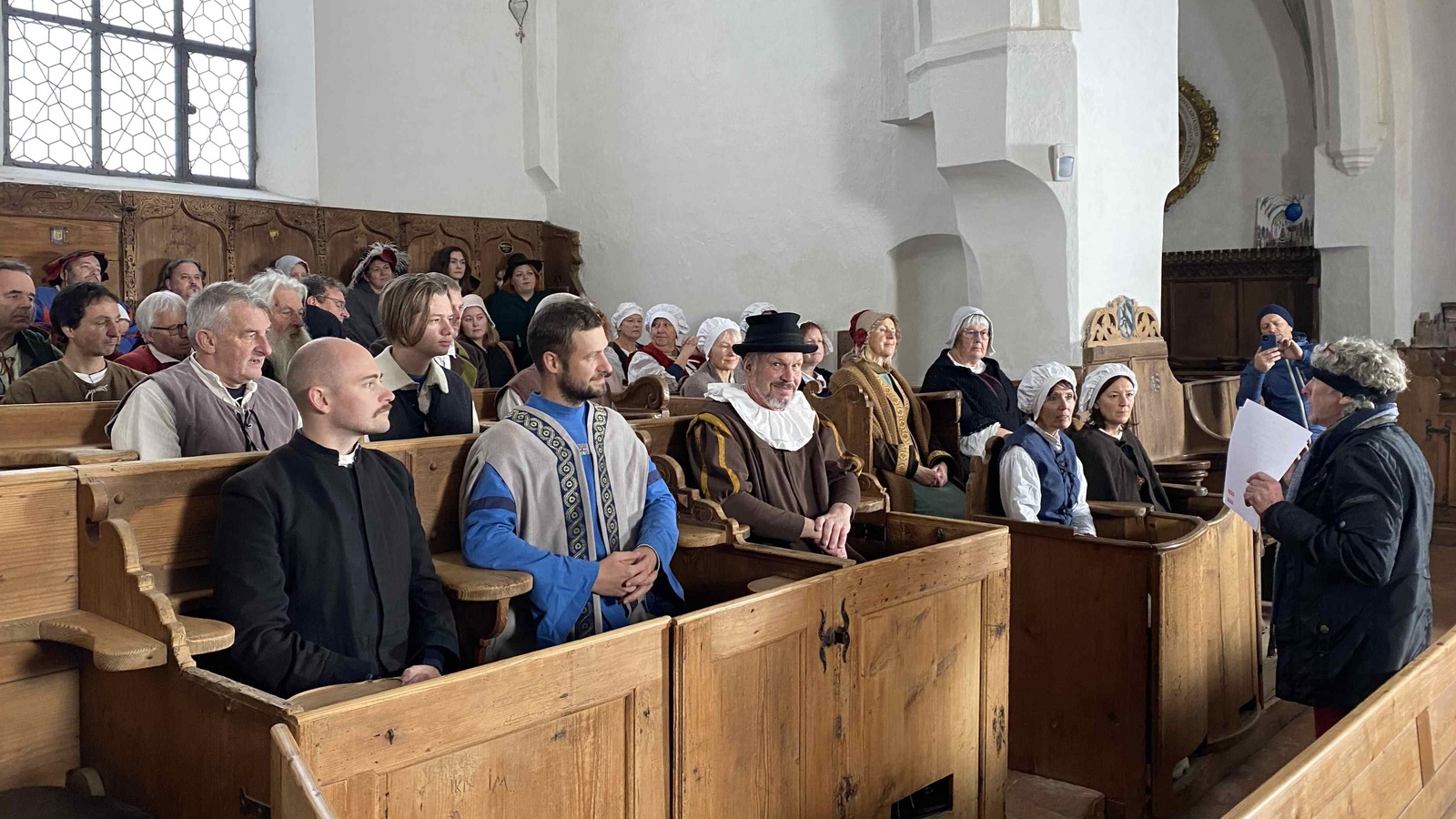 In der St. Martinskirche in Memmingen spielen Laienschauspieler:innen und Mitglieder aus Heimatvereinen als Statist:innen eine Szene mit dem Prediger Christoph Schappeler. Foto: Karl Milz