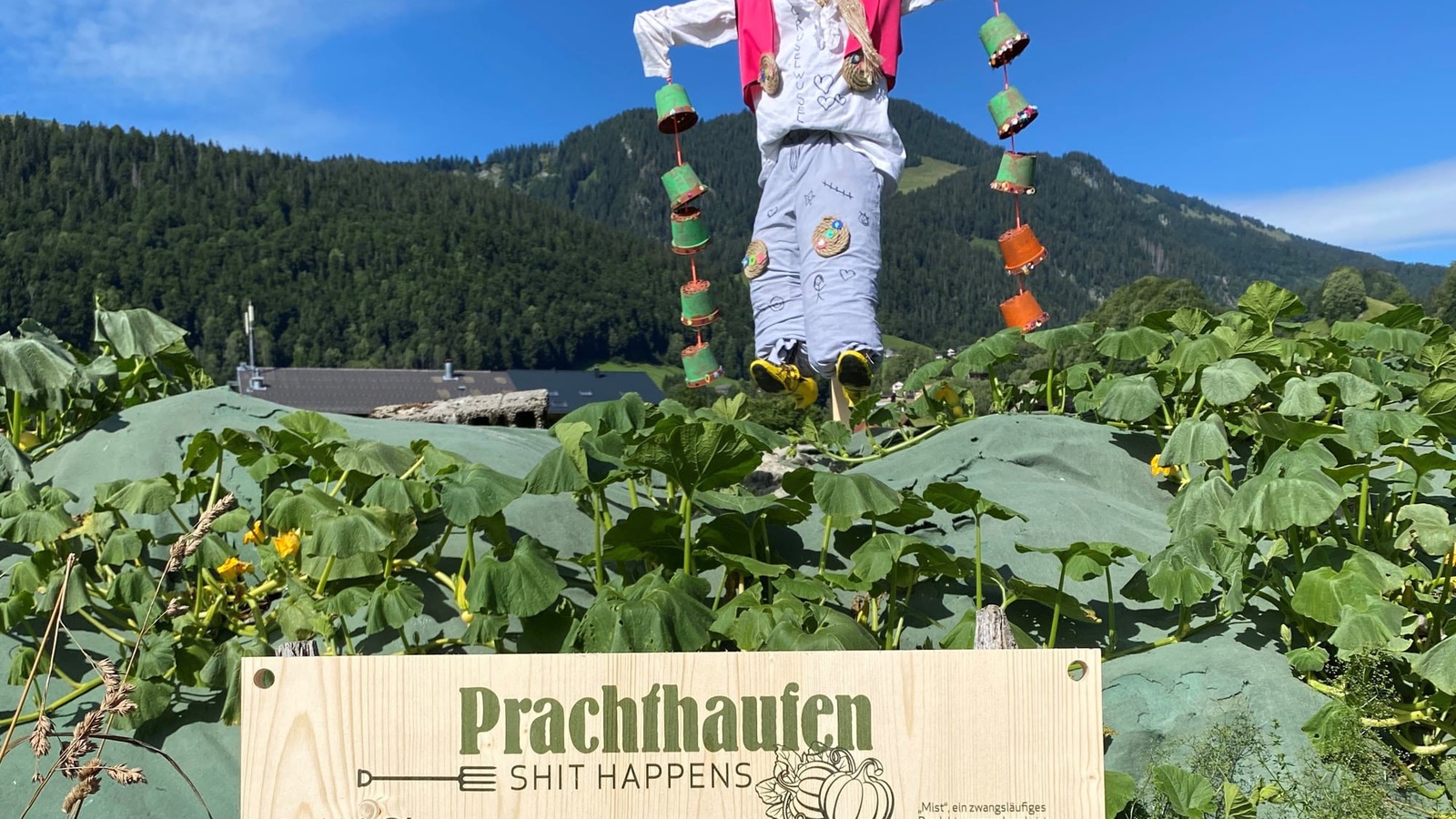 Von Kindern gebaute Vogelscheuchen dienen auf den Misthaufen als Blickfang und Schilder weisen auf das Projekt hin.